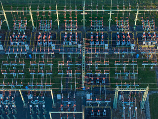 Aerial view of high-voltage electrical substation switchyard, energy infrastructure, complex grid infrastructure with insulators and lines.