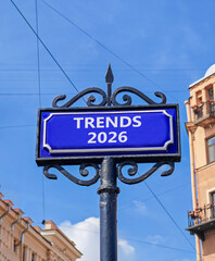 Obraz premium Trends 2026 new year symbol. Concept words Trends 2026 on beautiful blue road sign. Beautiful blue sky and buildings background. Business and Trends 2026 new year concept. Copy space.
