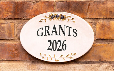 Grants 2026 symbol. Concept words Grants 2026 on beautiful white sign. Beautiful old brown brick...