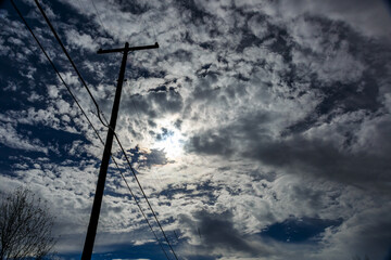 dynamic image of power lines with telephone pole against a moonlit cloudy sky at night