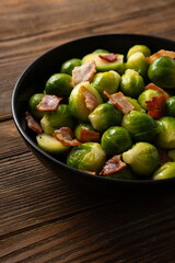 Brussels sprouts roasted with bacon in bowl wooden surface