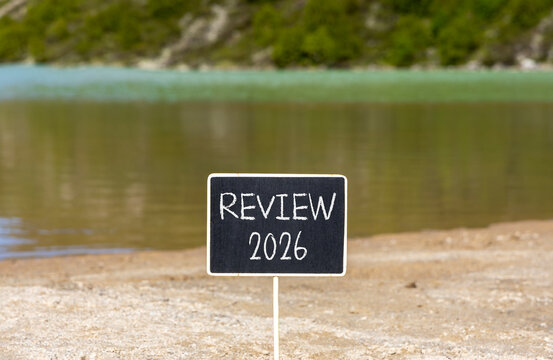 Review 2026 symbol. Concept words Review 2026 on beautiful black blackboard. Beautiful mountain lake sand beach background. Business and review 2026 concept. Copy space. - Powered by Adobe