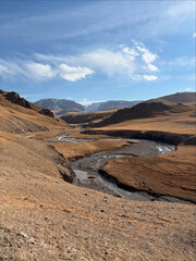 Golden valleys surround a gently winding mountain river.
