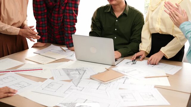 Architect and safety engineer celebrate success design building blueprint project on laptop on table with architectural document and wooden block scatter around at modern office. Closeup. Delineation.