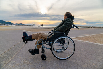 Young disabled woman in a wheelchair enjoying the landscape and the sea - Travel adventure