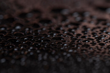 Black glass surface in water droplets, wet mirrored black glass in a large number of water drops