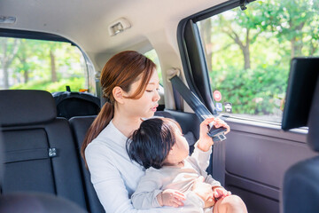 タクシーでシートベルトをする子連れのお母さん