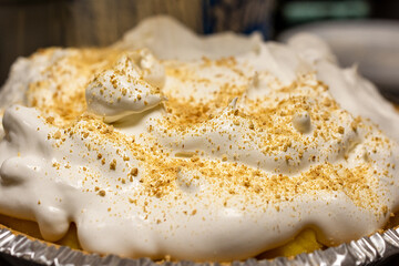 A finished banana cream pie covered in a thick layer of whipped cream, generously sprinkled with crushed graham cracker crumbs for decoration and texture.