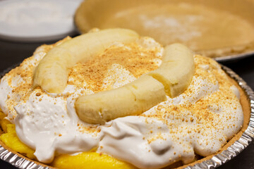 The finished banana cream pie, topped with fluffy whipped cream, graham cracker crumbs, and two whole peeled bananas for a perfect, decorative presentation.