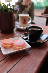 Friends Enjoying Coffee and Macarons at an Outdoor Cafe Table