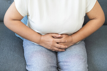 Sick asian senior woman in pain, hand holding belly, stomach pain from food poisoning, older hurt...
