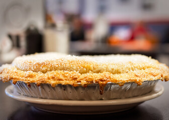 A dramatic side profile of a freshly baked cherry pie, highlighting the golden, flaky crust and sparkling sugar topping in a cafe setting.