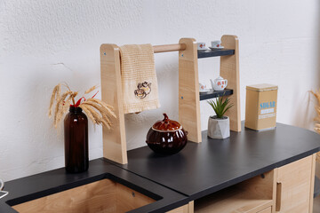 Close up of wooden toy kitchen countertop with towel rack and miniature tea set