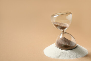Crystal hourglass and sand on beige background