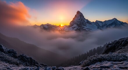 Dramatic mountain peak sunrise with clouds and snow in winter landscape
