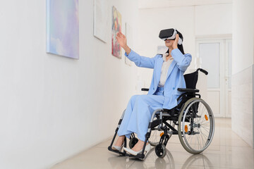 Young woman in wheelchair with VR glasses visiting art gallery