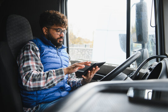 Truck driver using tablet for logistics in cabin - Powered by Adobe
