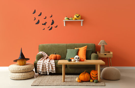Interior of living room decorated for Halloween with green sofa, table and pumpkins