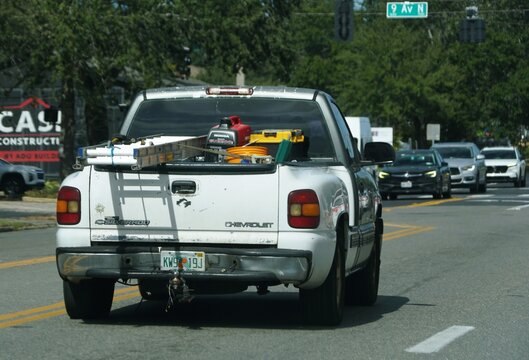 St Petersburg, Florida, U.S - Nov 9, 2025 - Rear view of a white Chevrolet Silverado pickup truck loaded with construction equipment, including a ladder and a Honda generator