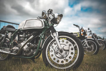 Fototapeta premium Classic motorcycles parked on grass under a cloudy sky