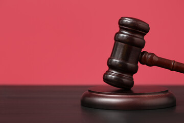 Judge's gavel on table against red background