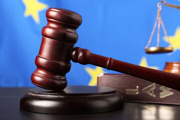 Judge's gavel on table against EU flag, closeup