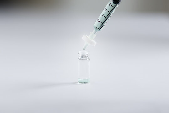 closeup of syringe sample solution with attached filter dispensing liquid sample into glass autosampler vial. This filtration step removes particulates during sample preparation for HPLC or LC-MS. 