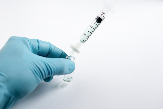 A scientist's hand grips a glass autosampler vial as a liquid sample is filtered through a microsyringe fitted with a filter membrane, removing particulates before HPLC or LC-MS analysis.