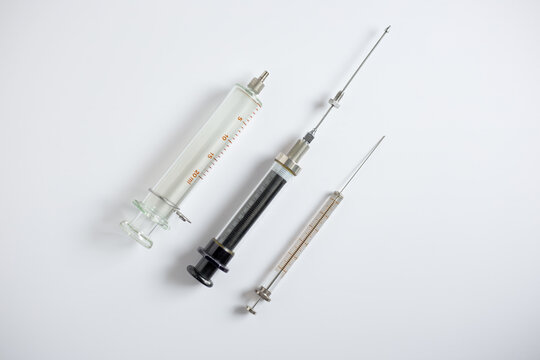 Three types of glass syringes for sample injection in HPLC and instrumental analysis, including 100 microliter, 10 mL, and 20 mL syringes, on a white background.