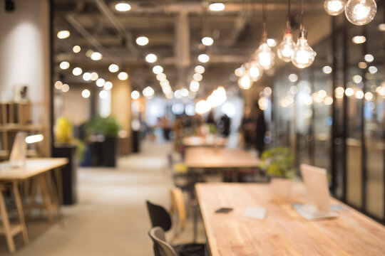 Defocused coworking space with warm lighting, modern interior, wooden tables, glass walls, and relaxed atmosphere, ideal for creative work and collaboration - Powered by Adobe