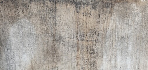 Fototapeta premium The view of an old, weathered concrete wall with cracks and natural aging patterns. Ideal for use as a textured background in design, architecture references, or artistic visual projects.