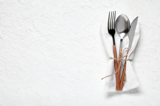 Silver cutlery and napkin on white background