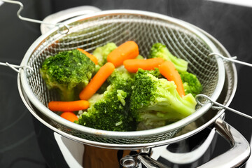 Frozen mixed vegetables steaming in metal colander on stove