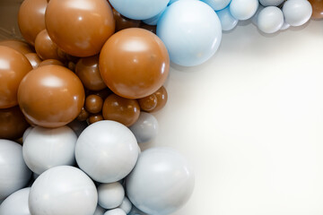 Colorful balloon garland with brown, blue, and white balloons on a clean white background. Minimalist party decoration layout with space for text.