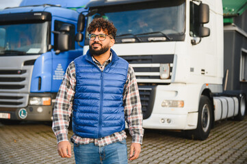 Professional truck driver standing proud in front of cargo vehicles