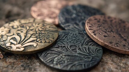 Detailed medium angle view of matte electroplated jewelry parts displaying subtle elegant metal finishes with artistic patterns.