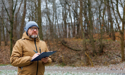Fototapeta premium Ecologist monitors the environment of a winter forest. Observing animals and birds in a snowy nature. Ecology control.