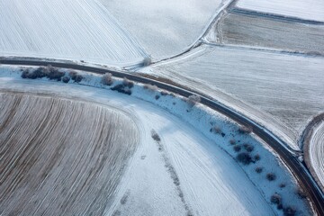Snow-covered fields and winding roads showcase winter beauty and serenity in a picturesque landscape reflecting seasonal charm and tranquility