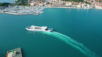 Aerial view of Split's vibrant harbor, with ferries, yachts, and the historic city against a backdrop of mountains and the clear Adriatic Sea. A bustling Croatian gem.