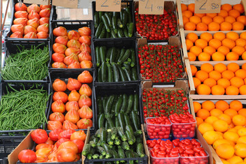 crates of fruit for sale at the produce stall featuring red tomatoes green zucchini and many other vegetables