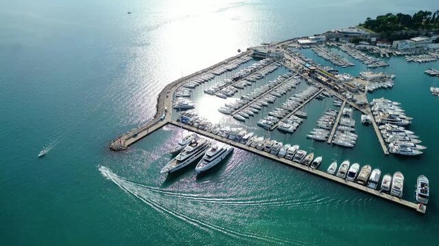Aerial view of Split's vibrant marina, bustling with luxury yachts and sailboats. A jet ski cuts through the sparkling turquoise Adriatic Sea under bright midday sun.