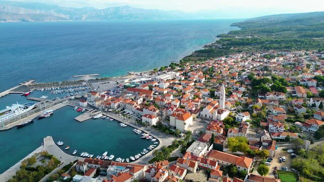 Aerial view of Supetar, Brac Island, Croatia. Picturesque harbor, red-tiled roofs, and turquoise Adriatic Sea under a bright morning sky. Mediterranean beauty.