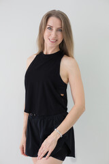 Smiling Woman in Black Athletic Wear Posing Against White Background