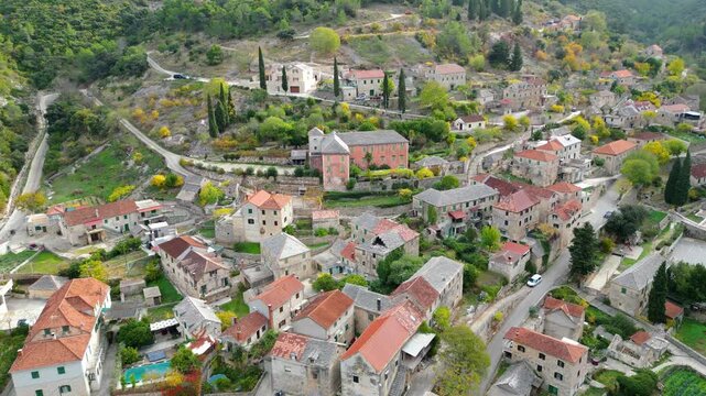 Aerial view of Dol, a picturesque village nestled in a lush valley on Brac Island, Croatia. Autumn colors highlight the traditional stone houses and terraced hillsides.