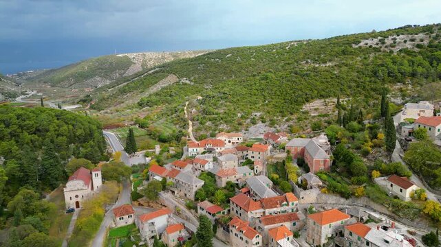 Aerial view of Dol, a charming village nestled in a lush valley on Bra? Island, Croatia, under a dramatic cloudy sky. Mediterranean beauty.