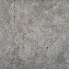 Close-up of a beige-gray travertine or marble tile with natural cracks and speckles. Repetitive, natural stone texture for creating backgrounds, architecture, and construction themes.