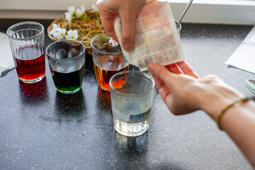 A woman adds dye powder to glasses in preparation for dyeing Easter eggs