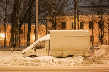 a small truck with a van parked on the side of the road, covered in snow
