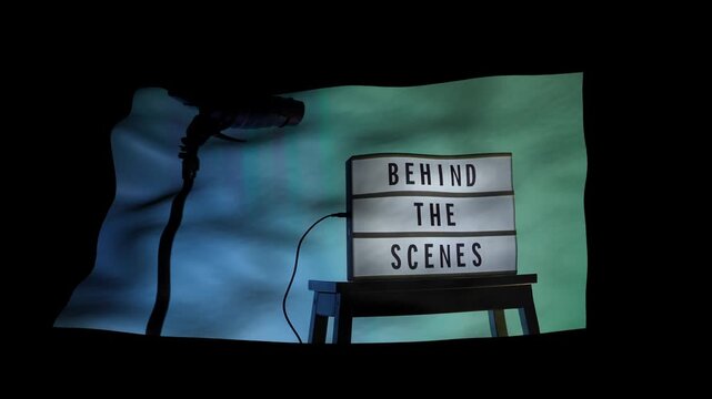 A cinematic view of a Behind the Scenes sign on a wooden stool under professional studio lighting. The frame includes a timestamp and recording elements mimicking a video camera interface. Close up.