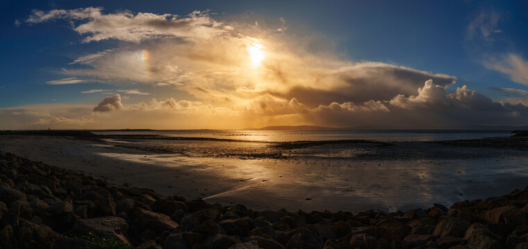 Galway seascape with dramatic sunrise clouds over the Aran Islands and Salthill Bay in the North Atlantic Ocean at low tide, in Connacht Province, Ireland.
